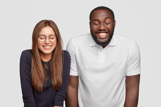 Un chico de piel oscura sonriente y feliz y su novia se ríen positivamente por una broma divertida