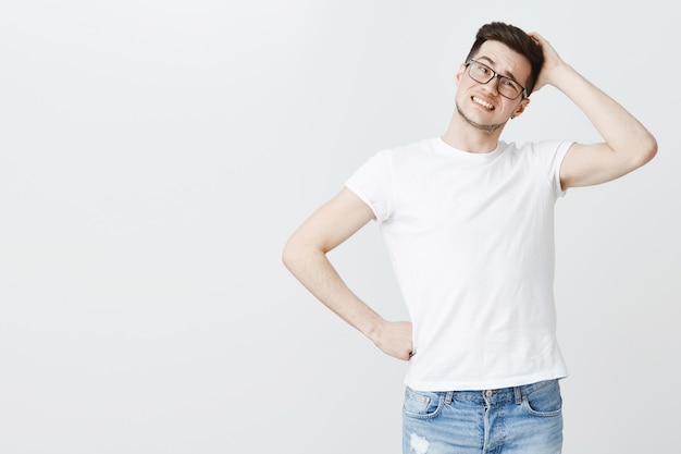 Foto gratuita chico preocupado en gafas rascándose la cabeza inseguro, pensando