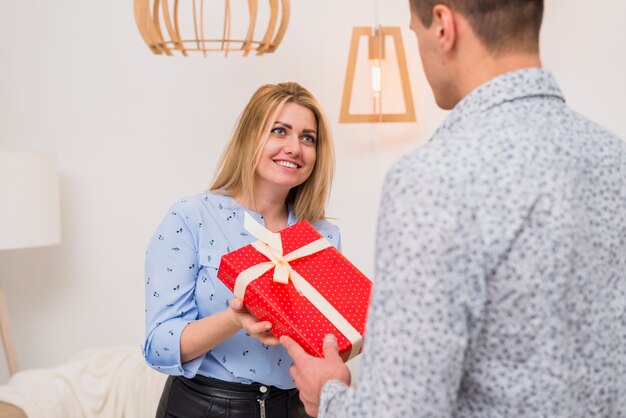 Chico presentando caja de regalo a señora feliz