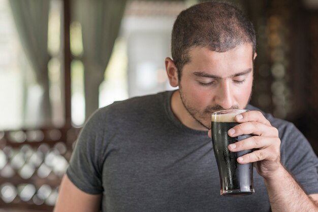 Chico que huele cerveza en pub