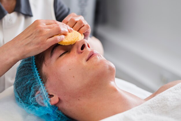 Chico recibiendo tratamiento facial en salón de belleza