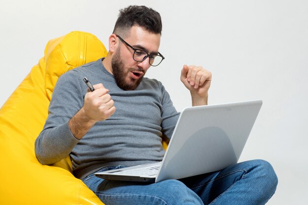 Un chico se regocija mientras trabaja en la computadora portátil