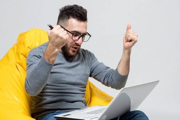 Un chico se regocija mientras trabaja en la computadora portátil