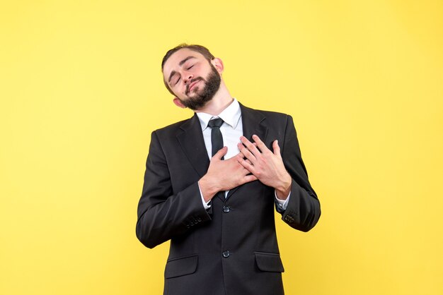 Chico romántico barbudo sosteniendo sus manos en su corazón