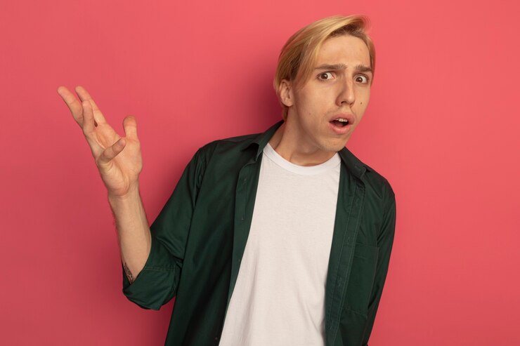 Foto gratuito chico rubio joven confundido con camiseta verde extendiendo la mano
