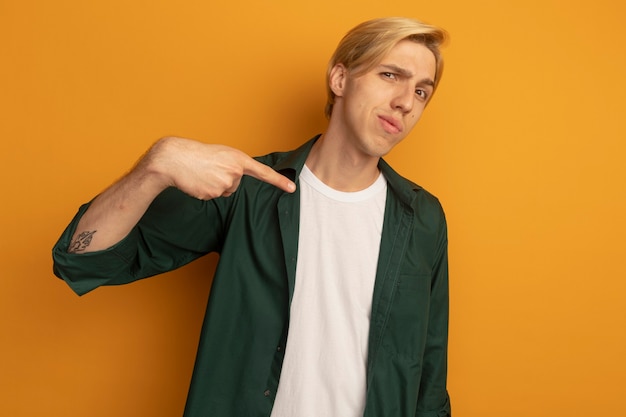 Chico rubio joven disgustado con puntos de camiseta verde al lado