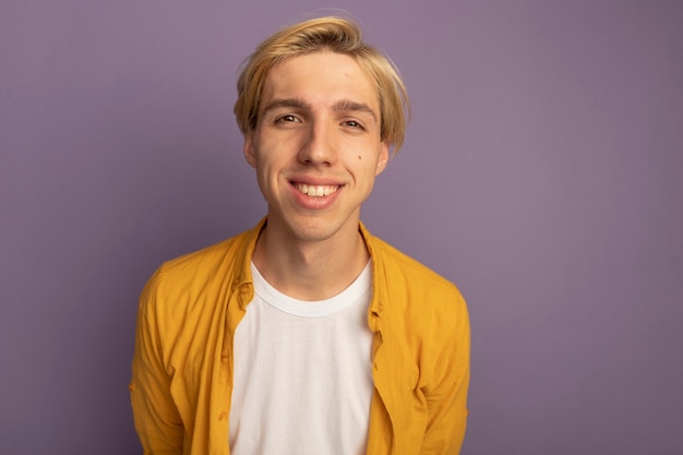 Chico rubio joven sonriente con camiseta amarilla cogidos de la mano en la cintura