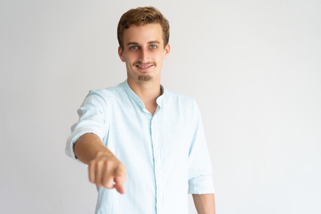 Chico rubio sonriente positivo que le elige. Hombre caucásico joven que señala el dedo en la cámara.