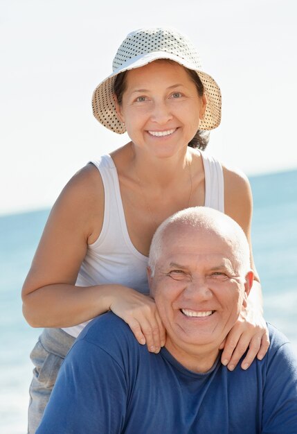 Chico senior feliz y chica madura juntos contra el mar