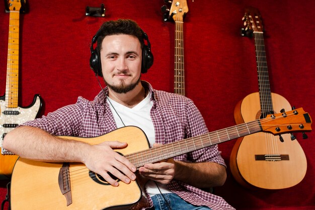 Chico sentado y sosteniendo una guitarra en el estudio