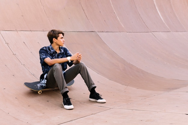 Chico skater joven sentado en medio tubo