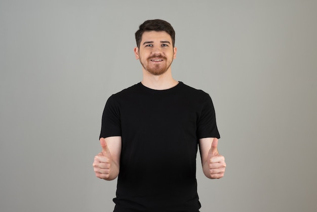 Chico sonriente haciendo un gesto con el pulgar hacia arriba en un gris.