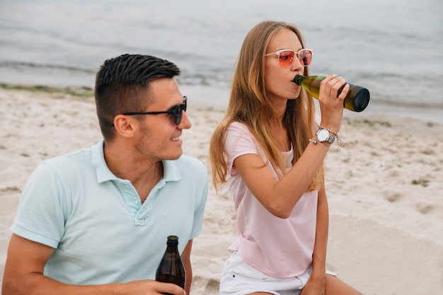 Chico sonriente y linda chica pasar tiempo con placer en la playa, junto al mar