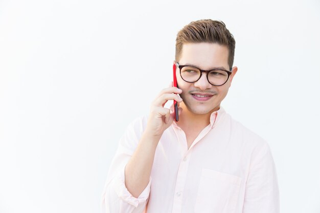 Chico sonriente pensativo en anteojos llamando al celular