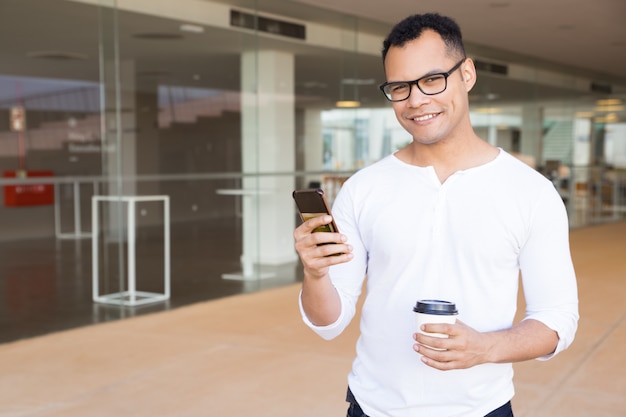 Chico sonriente con smartphone mirando a cámara