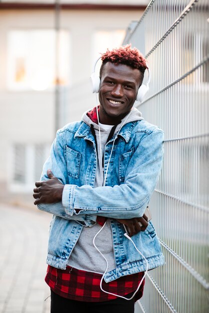 Chico sonriente de tiro medio con auriculares y brazos cruzados