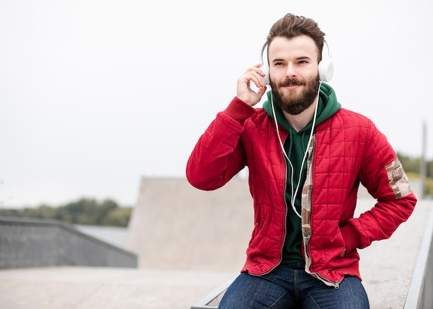 Chico sonriente de tiro medio con auriculares sentado