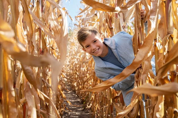 Chico sonriente de tiro medio en campo de maíz
