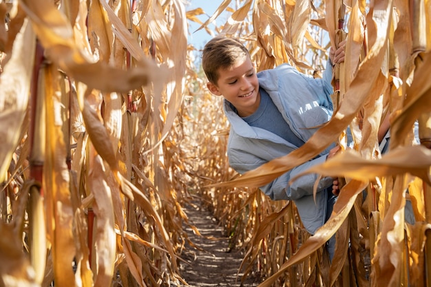 Chico sonriente de tiro medio en campo de maíz
