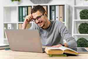 Foto gratuita chico sonriente de tiro medio estudiando con su computadora portátil