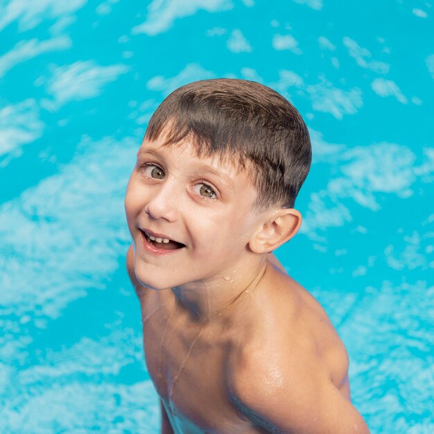 Chico sonriente de tiro medio en la piscina