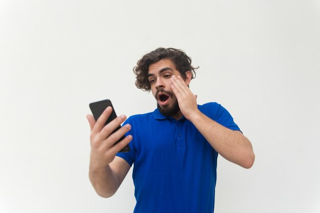 Chico sorprendido con mensaje de lectura de teléfono inteligente, mirando la pantalla