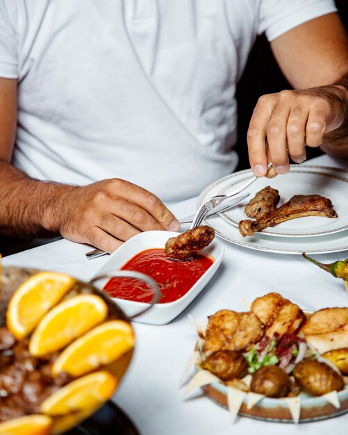 Chico sumergiendo kebab en salsa