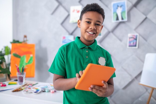 Chico con tablet sonriendo a la cámara en el interior