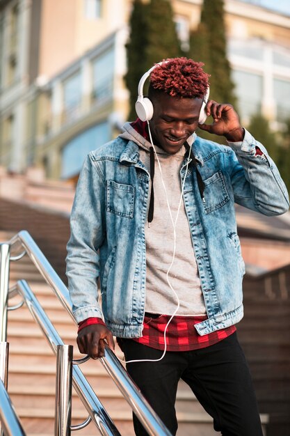 Chico de tiro medio con auriculares bajando las escaleras