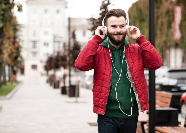 Chico de tiro medio con auriculares caminando en la ciudad