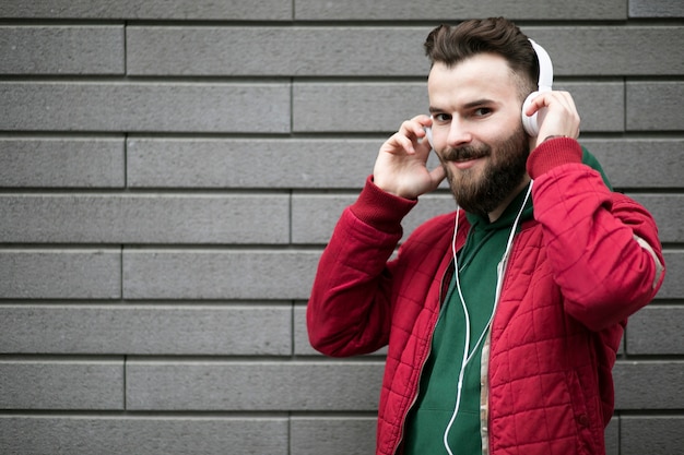 Chico de tiro medio con auriculares cerca de la pared de ladrillo