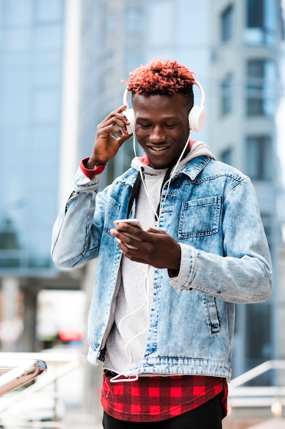 Foto gratuita chico de tiro medio con auriculares mirando el teléfono