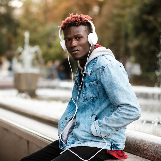 Chico de tiro medio con auriculares sentado