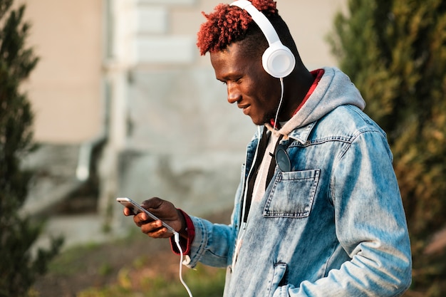 Chico de tiro medio con auriculares y teléfono inteligente