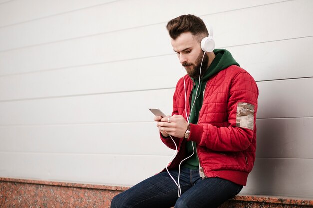 Chico de tiro medio con auriculares y teléfono inteligente