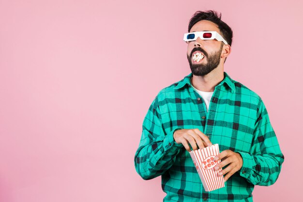 Chico de tiro medio con la boca llena de palomitas de maíz