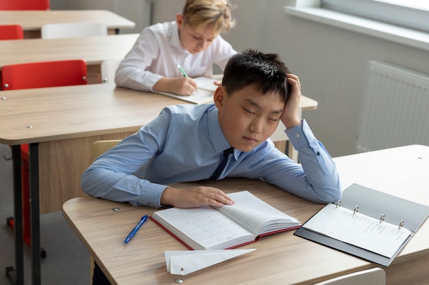 Chico de tiro medio durmiendo en la escuela