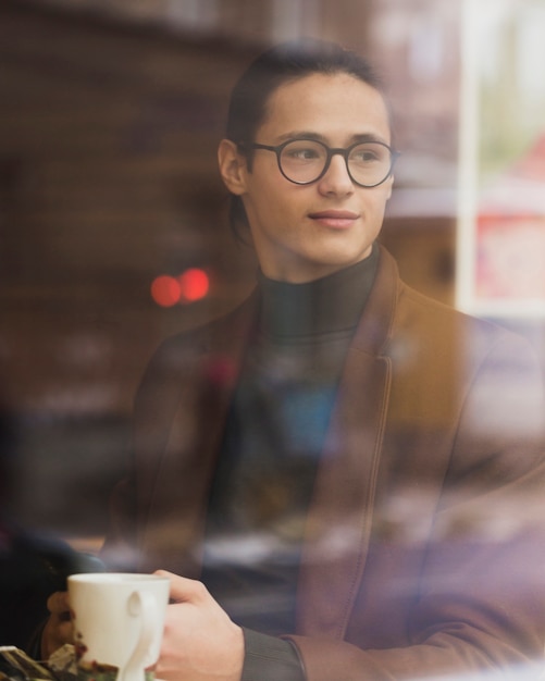 Chico de tiro medio con gafas sosteniendo la taza