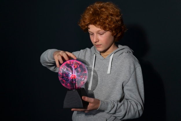 Foto gratuita chico de tiro medio interactuando con una bola de plasma.