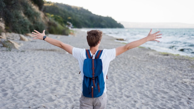 Foto gratuita chico de tiro medio con mochila en la playa