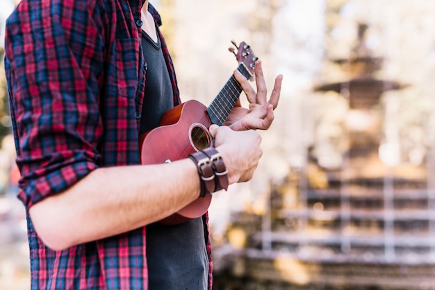 Chico tocando el ukelele junto a una fuente