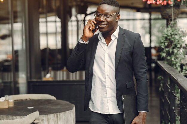 Chico de traje negro. Hombre con un teléfono móvil. Hombre de negocios en la oficina.