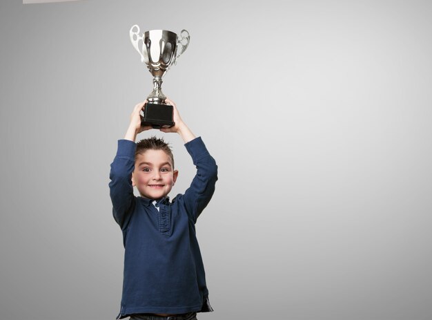 Chico con un trofeo encima de su cabeza