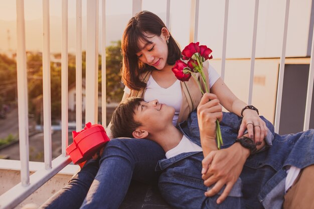 Chico tumbado en las piernas de su novia con rosas en la mano