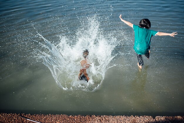 Chicos activos saltando de troncos en el agua.