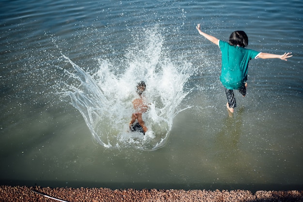 Chicos activos saltando de troncos en el agua.