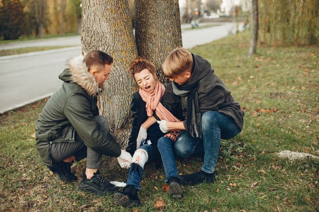 Los chicos ayudan a una mujer. Chica con una pierna rota. Brindar primeros auxilios en el parque.