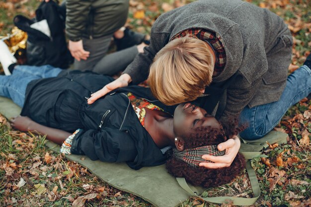 Los chicos ayudan a una mujer. Niña africana yace inconsciente. Brindar primeros auxilios en el parque.