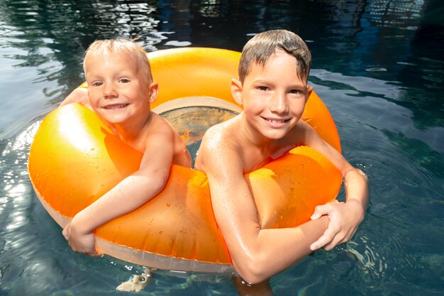 Chicos divirtiéndose en la piscina con flotador de piscina.