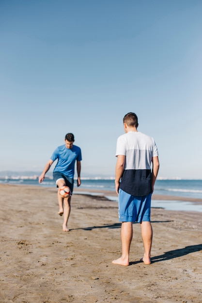 Chicos jugando al fútbol en la playa